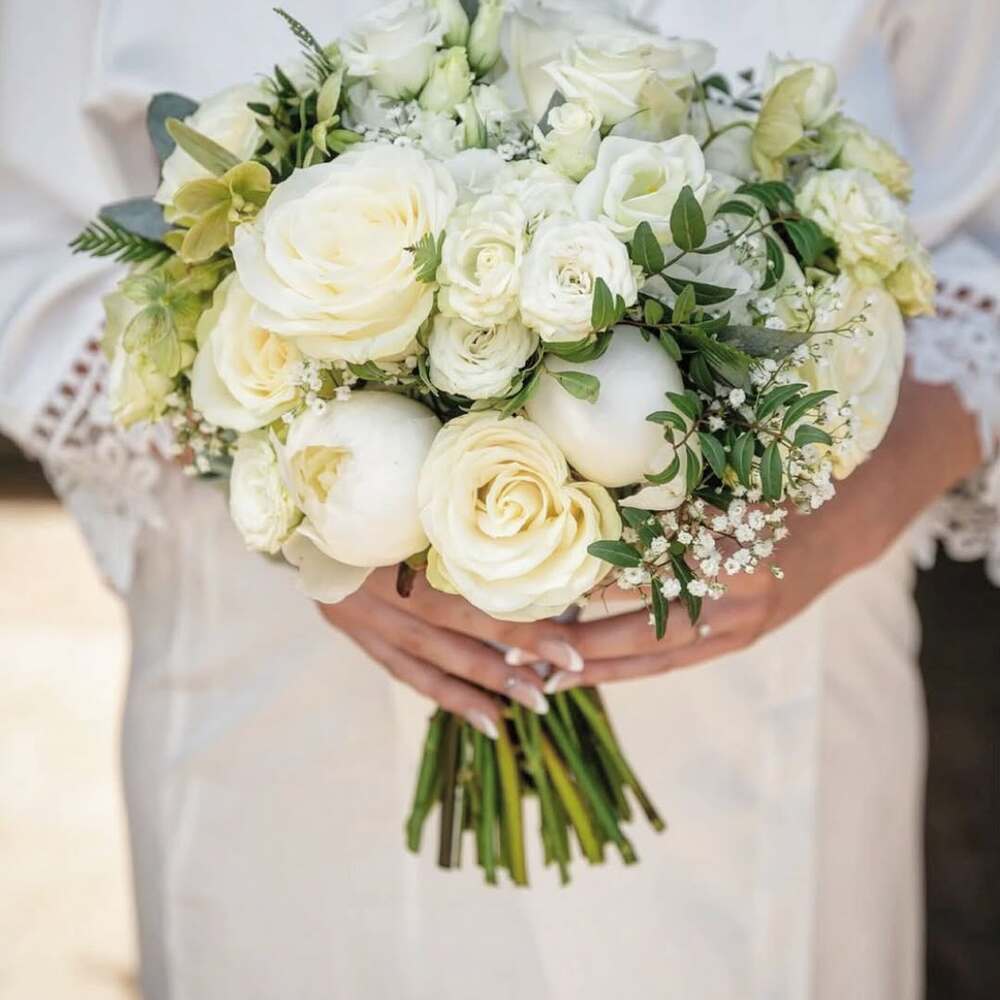 Elegant bride holding white peony bouquet