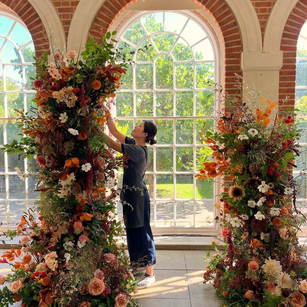 Florist creating autumnal flower installations at venue