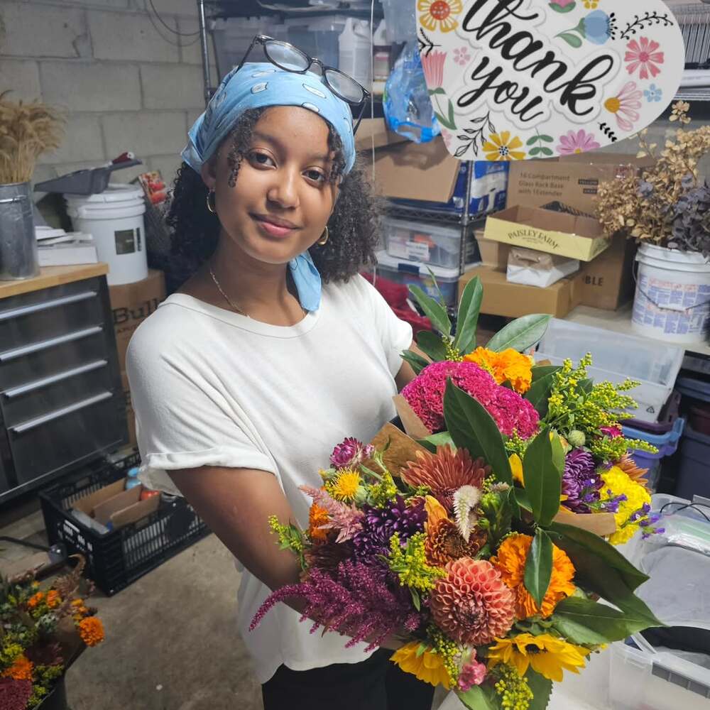 Young woman holding vibrant flowers indoors