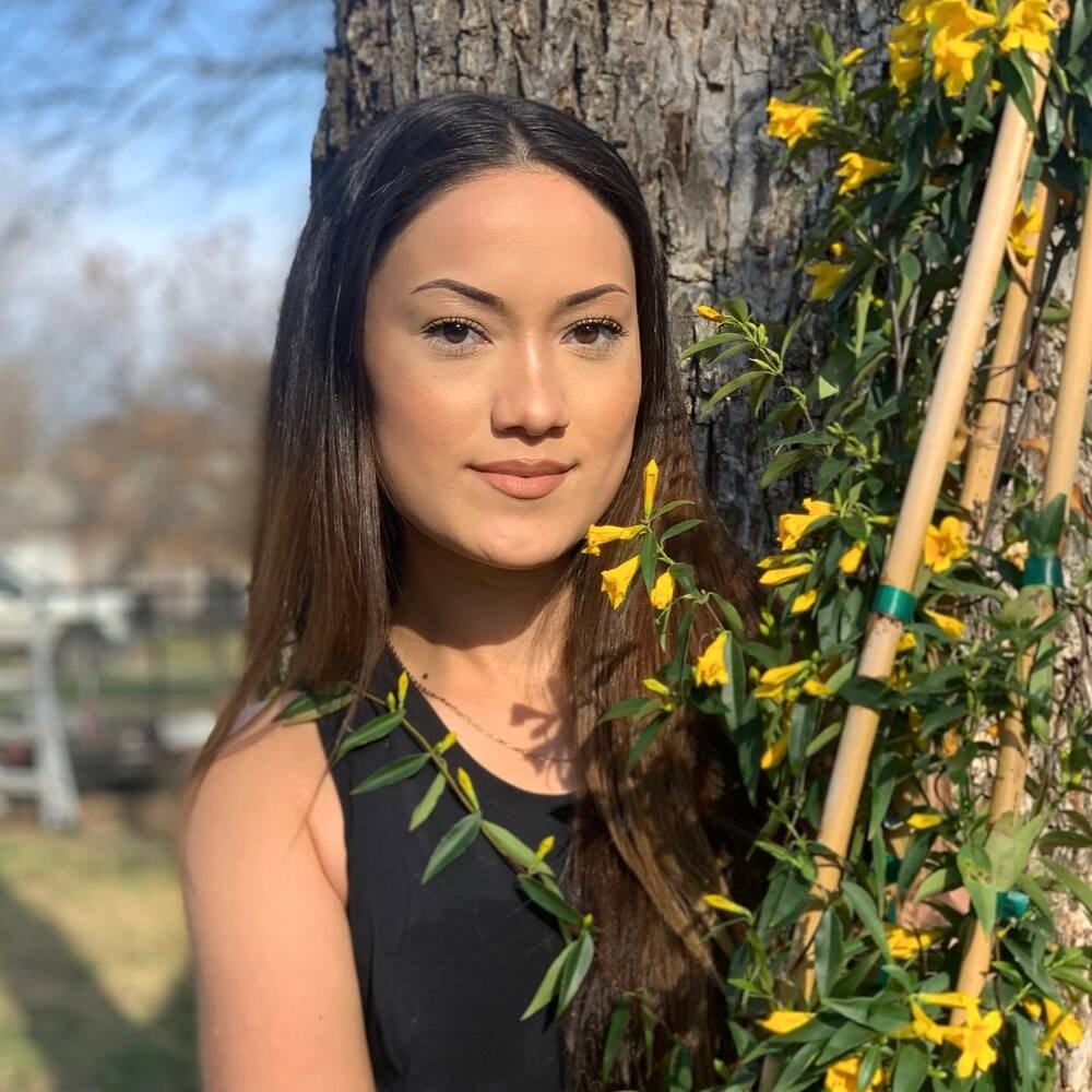 a woman holding a bunch of yellow jessamine