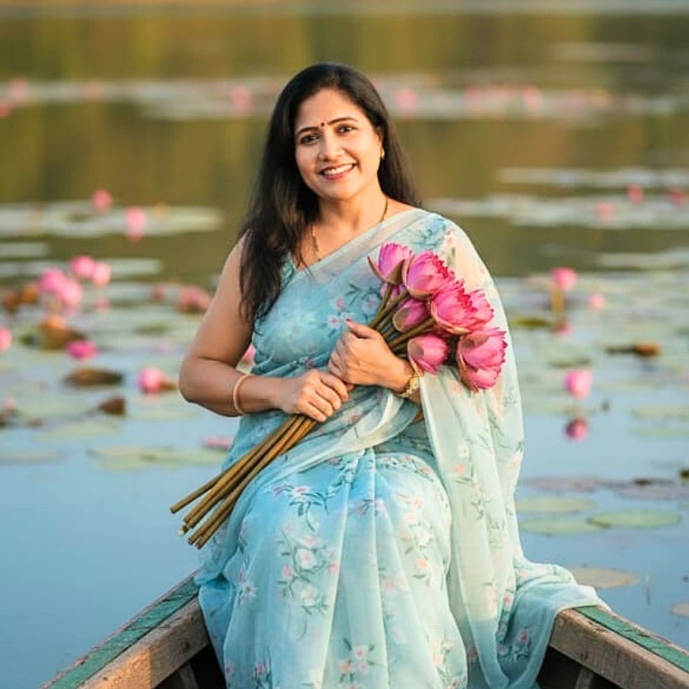 a lady holding a bunch of lotus flowers and is sailing in a pond full of lotus flowers
