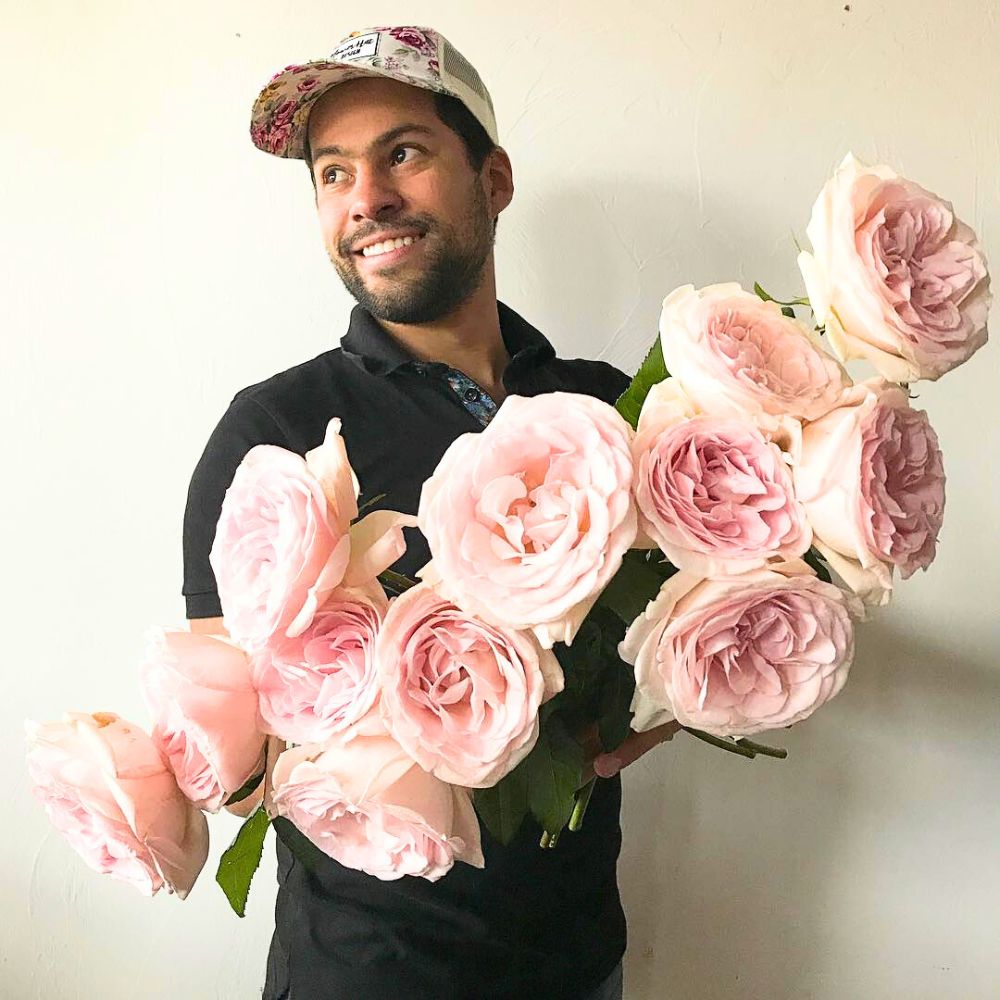 A man holding a bunch of Rose Prince Jardinier he bought from Parfum Flower Company