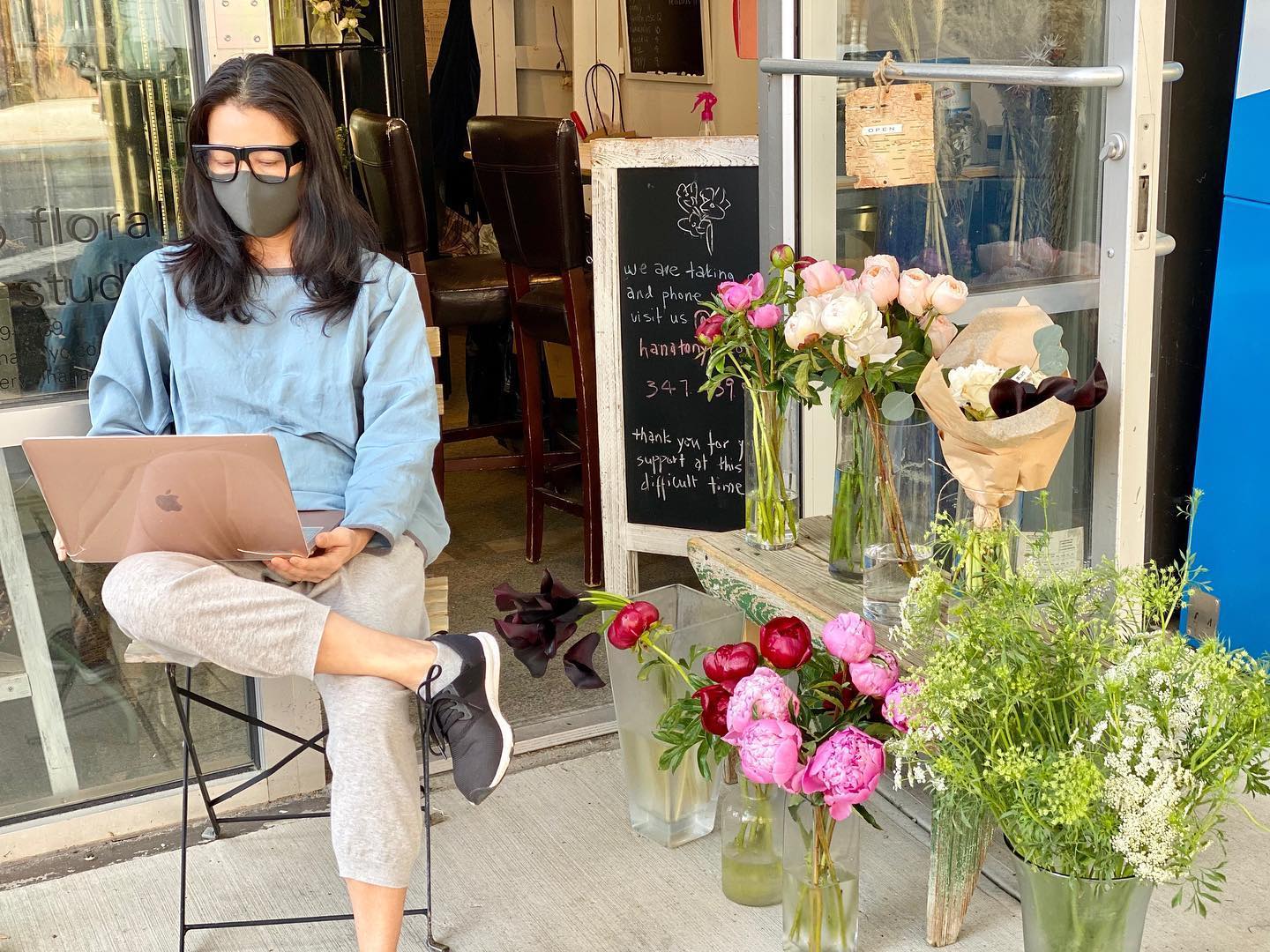 designer sitting outside her store and processing orders online - Hanato Floral Design NYC