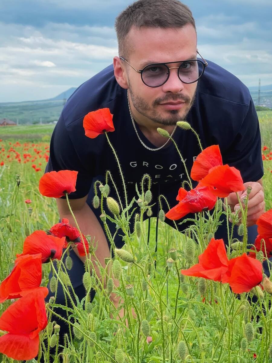 Man leaning over red poppy flowers