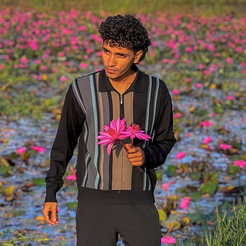 A man holding two stems of lotus flowers