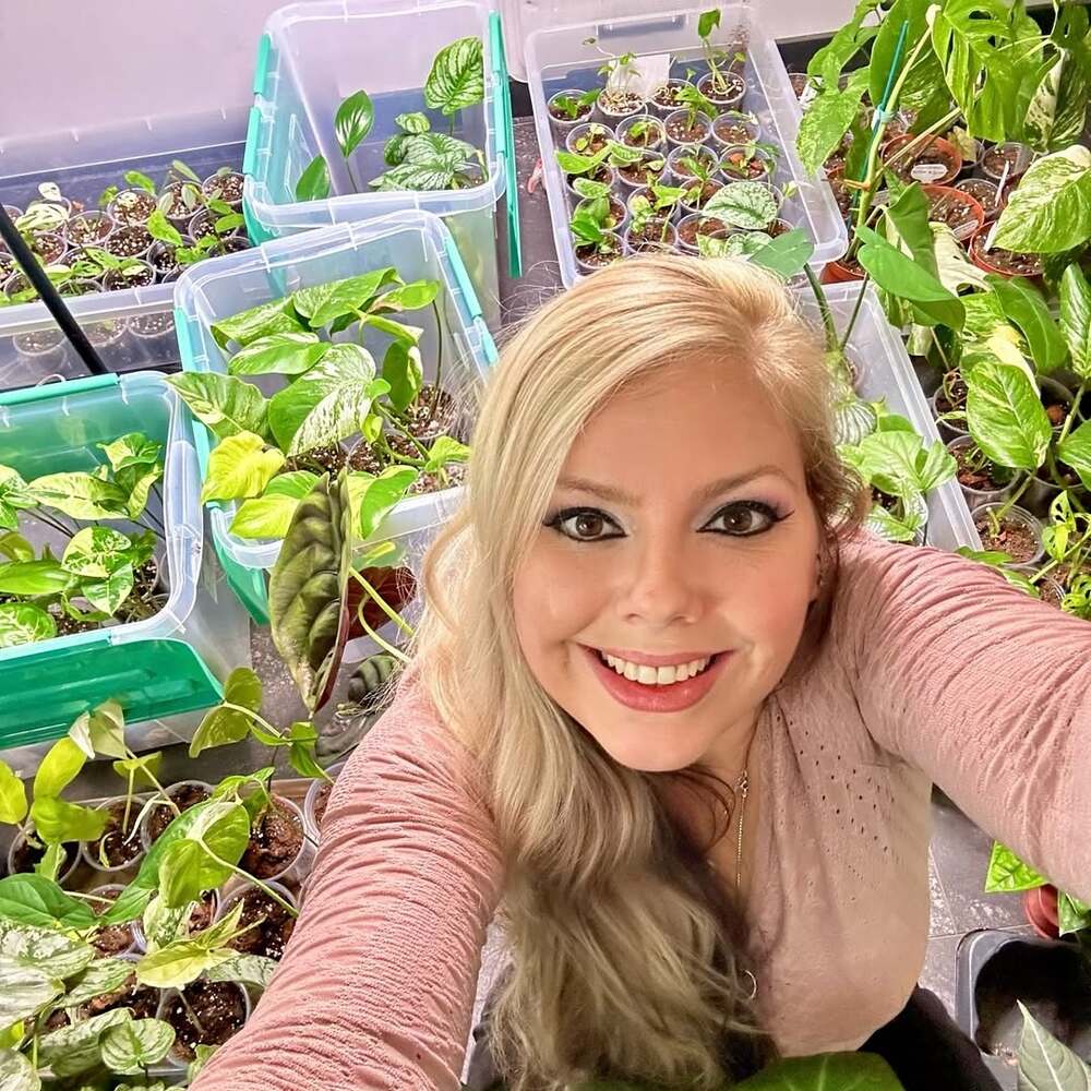 Woman smiling with indoor plant cuttings