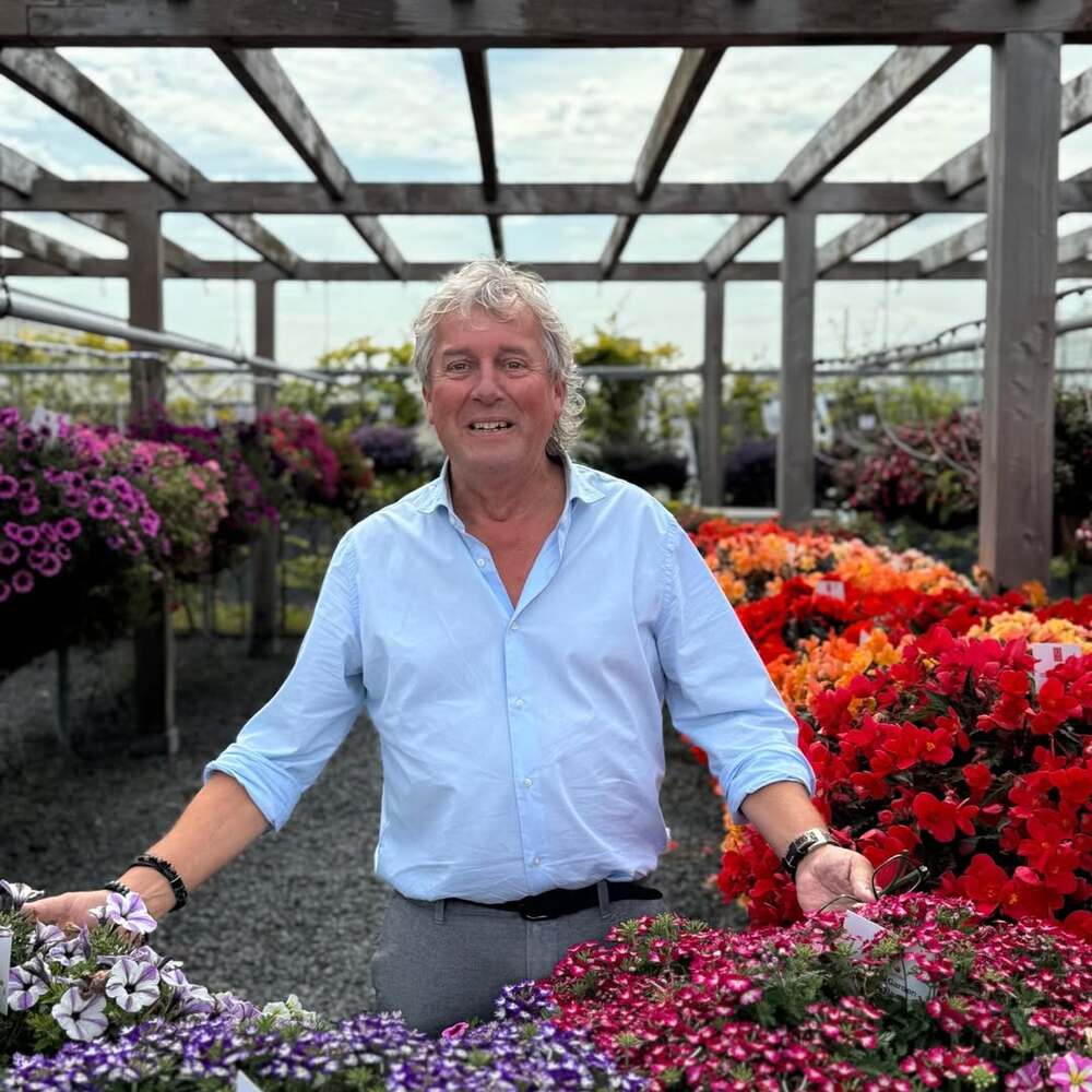 A man smiling in a greenhouse