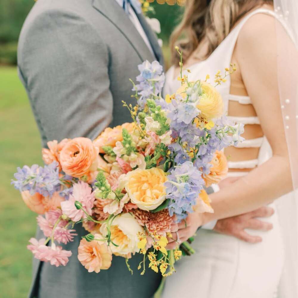 A bride and groom holding colorful wedding flowers