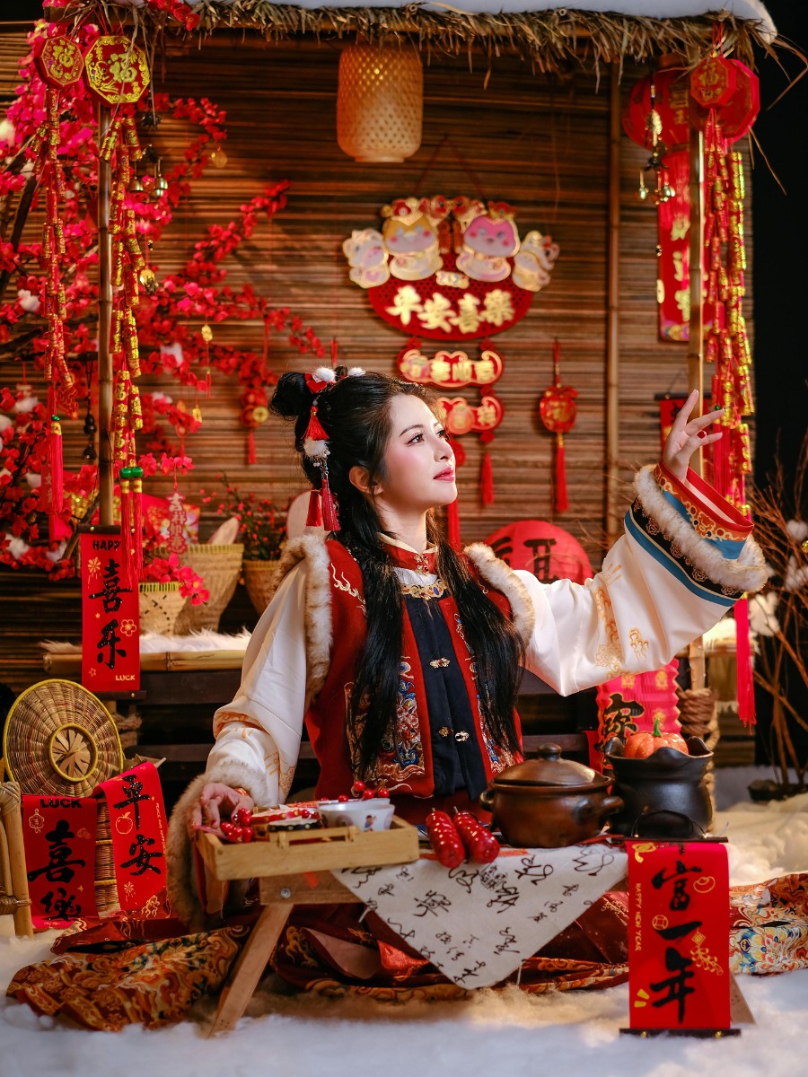 Lady in Hanfu attire preparing for Chinese New Year and beautiful flowers used in decor in the backdrop