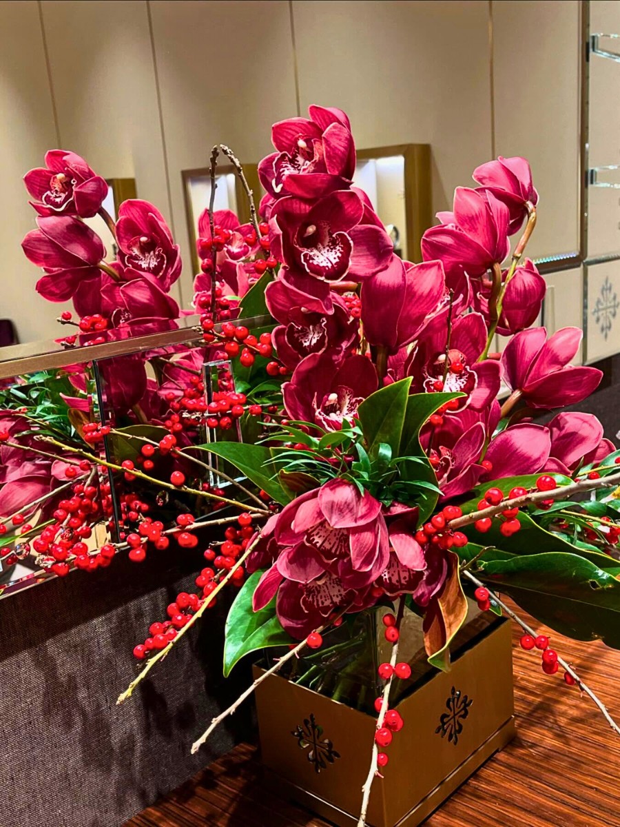 Red cymbidium orchids, magnolia leaves and ilex berries