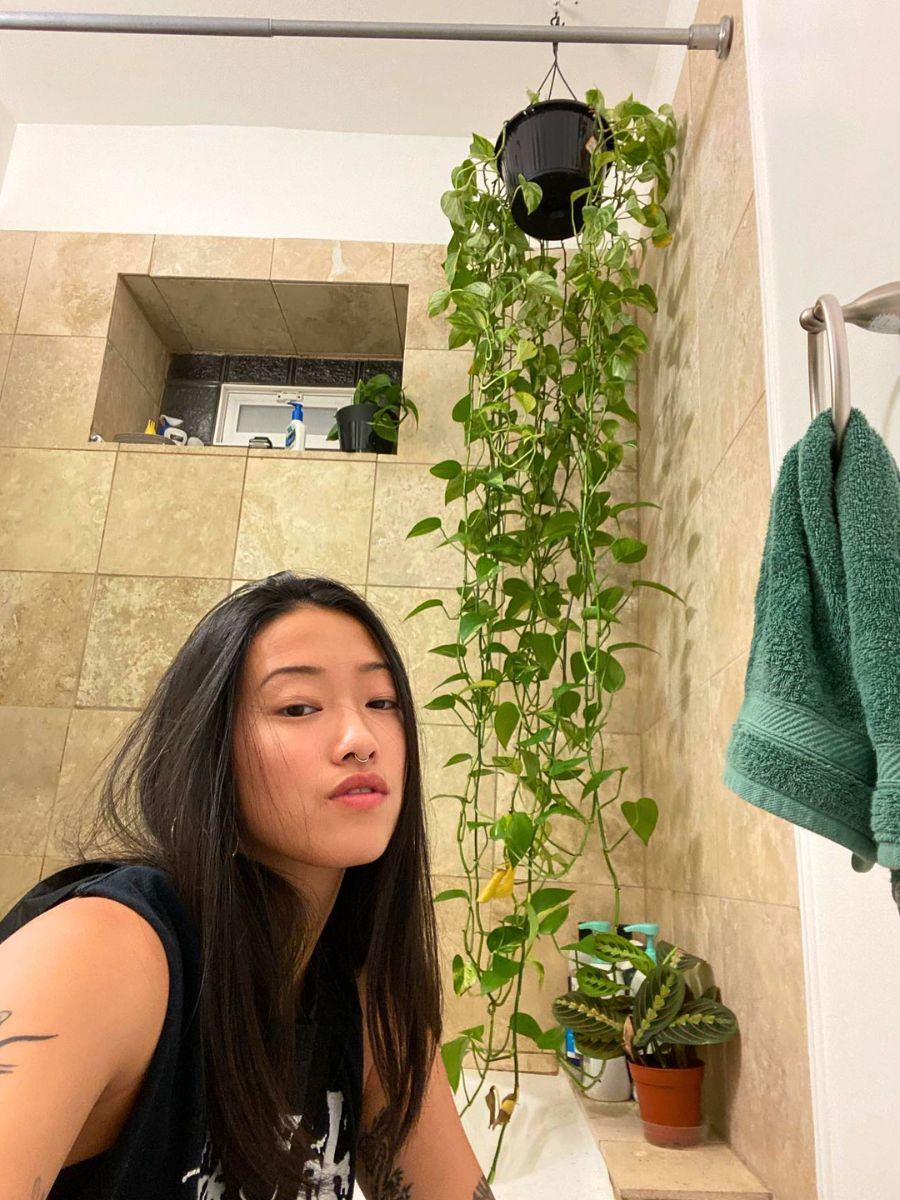Taking a selfie next to a pothos plant in a bathroom
