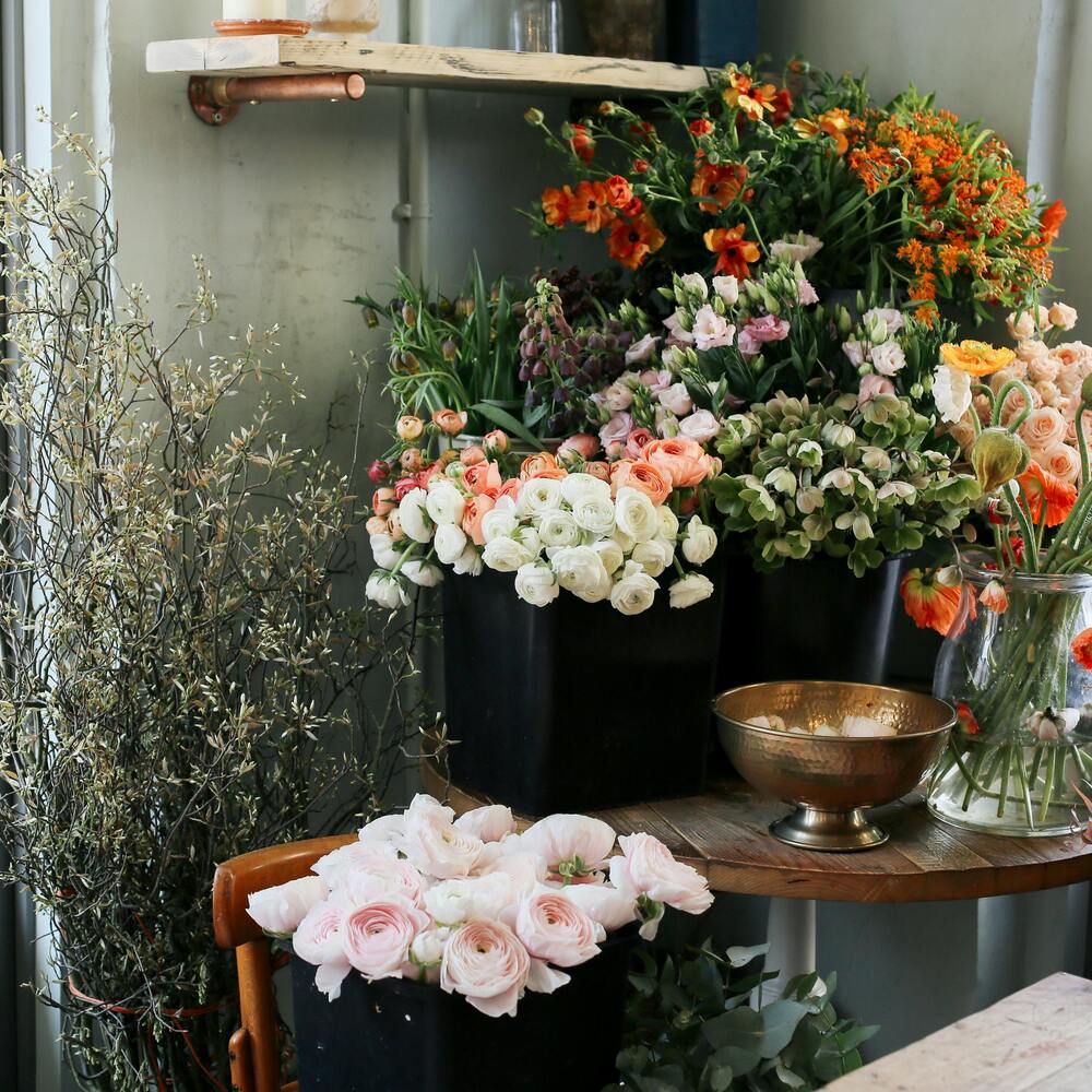 A modern florist shop with wood and metal display tables holding fresh bouquets