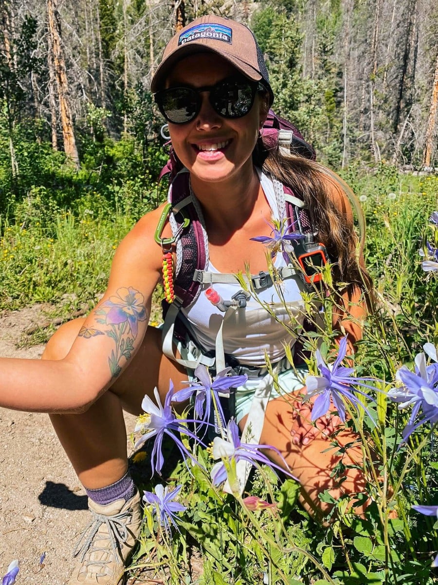 A woman with a tattoo of the Rocky Mountain columbine flower on her arm.
