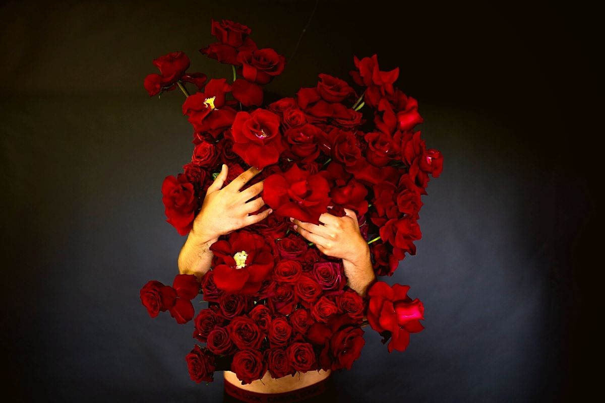 Beautiful woman with red roses. Gift with love. Beautiful smiling girl  holding large bouquet of red roses on black background. Beautiful woman  with red rose bouquet. Stock Photo