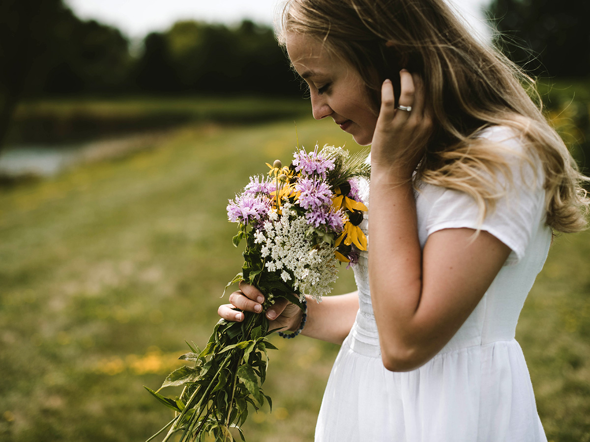 Woman smelling flowers by Samantha Gades