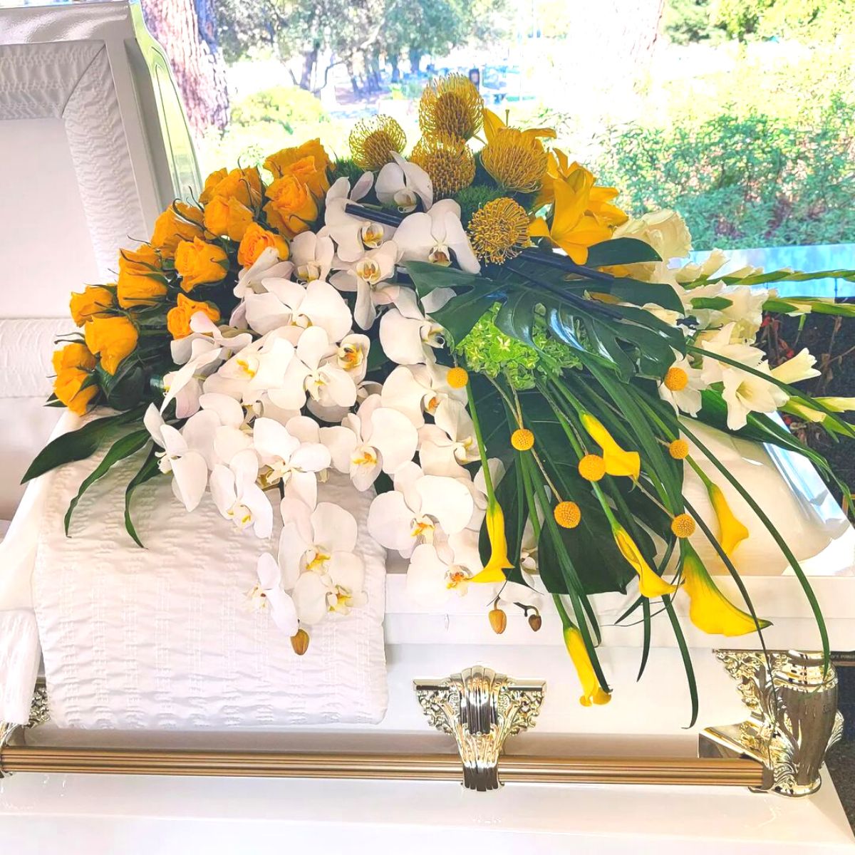 White orchids mixed with yellow blooms as sympathy flowers