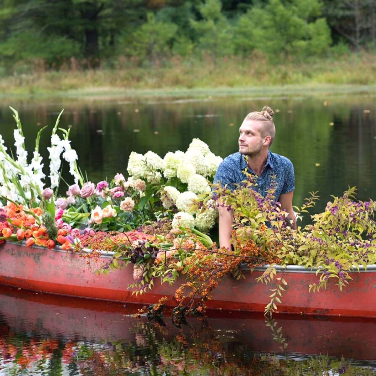 Connor Nesbit surrounded by flowers on a boat