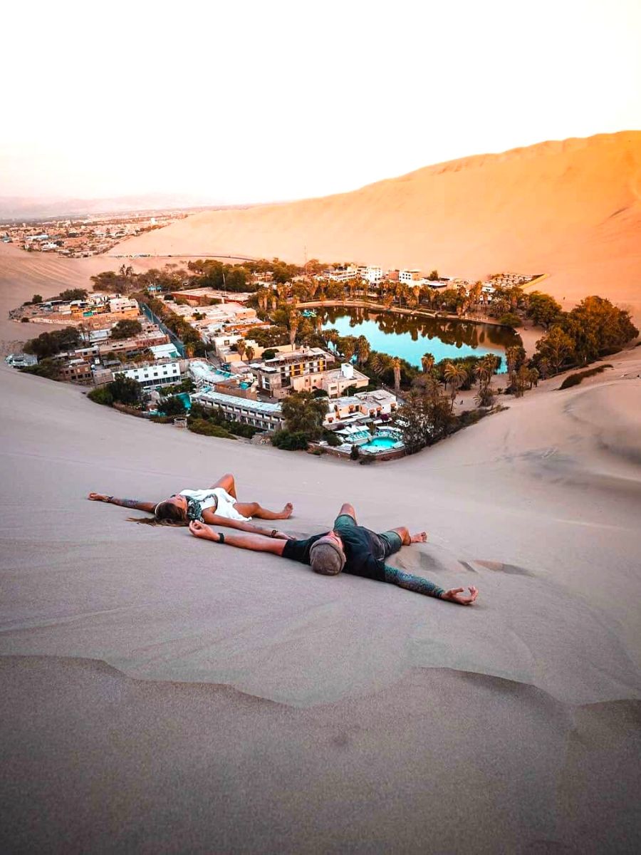 Two people laying in the sand dunes at Huacachina