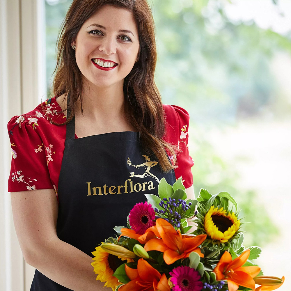Interflora florist with apron and lily and helianthus bouquet