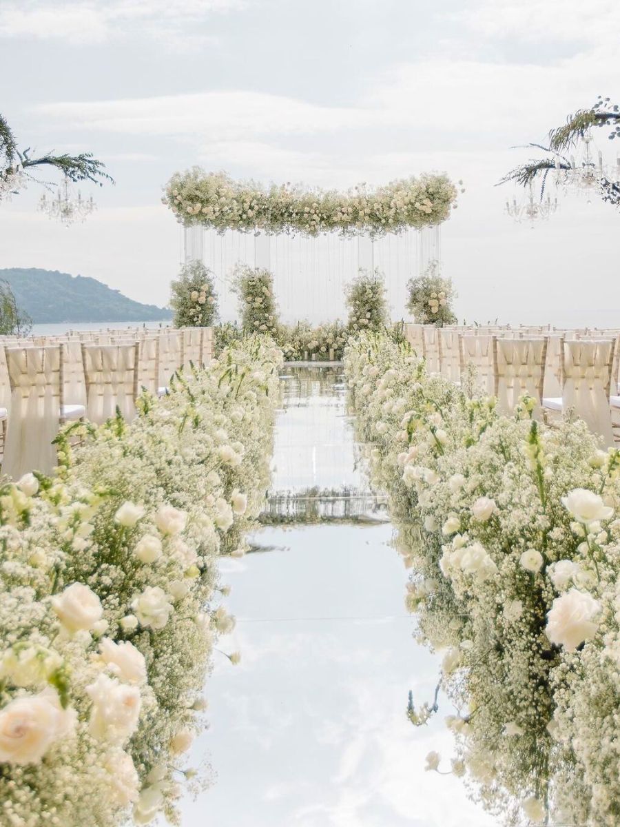 White wedding aisle decorated with hundreds of white flowers