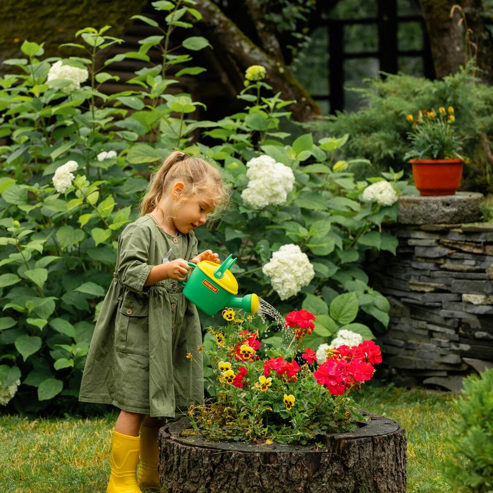 Cute girl watering to garden flowers