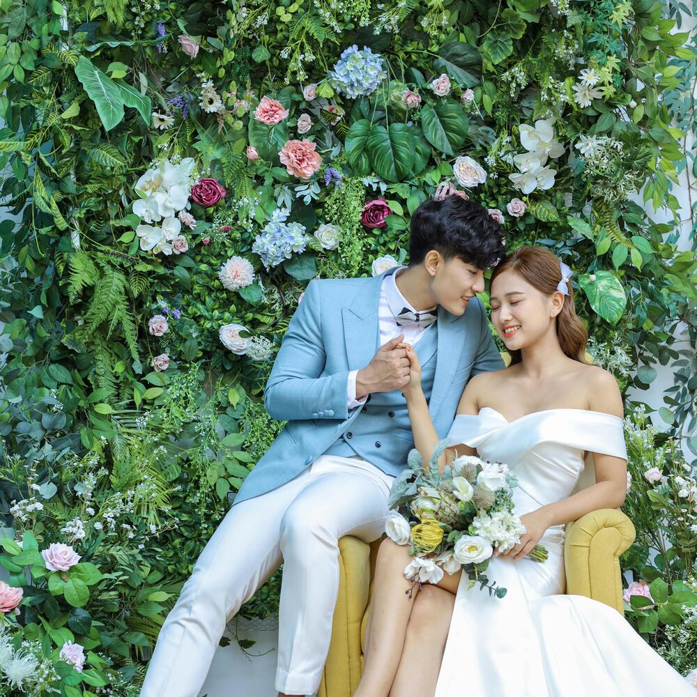 Couple posing with background flower arrangement