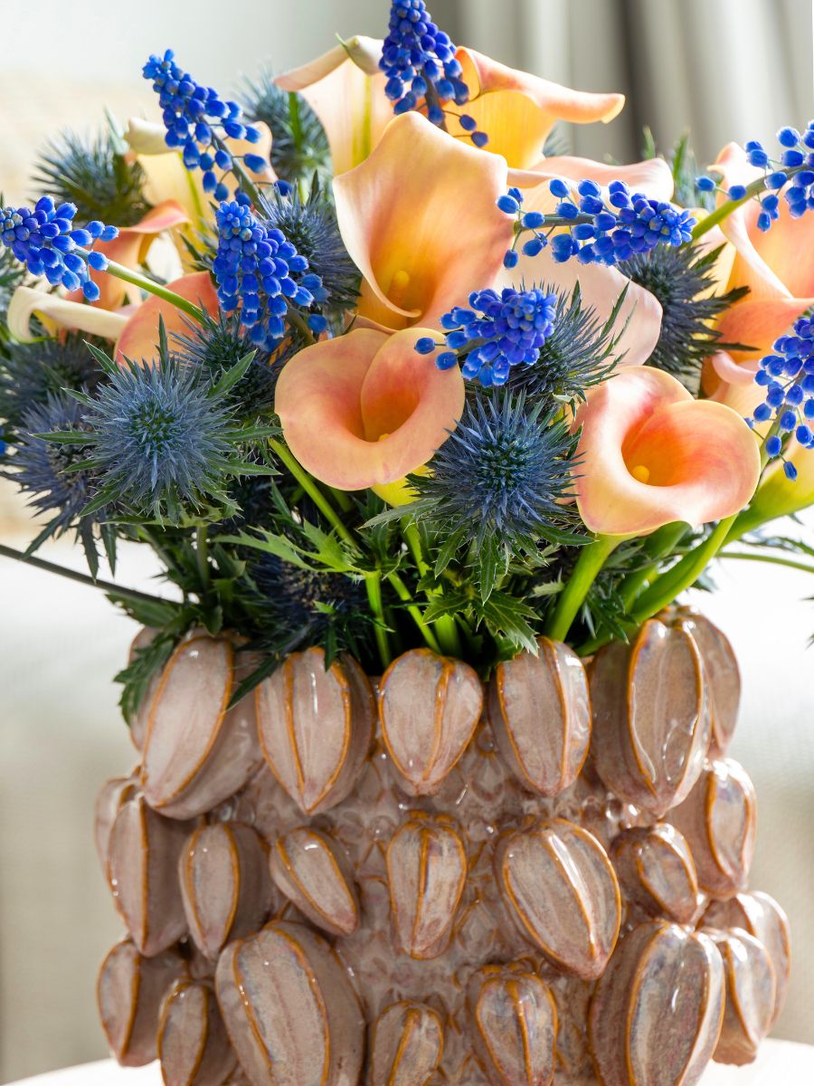 A peachy arrangement of calla lilies and blue flowers