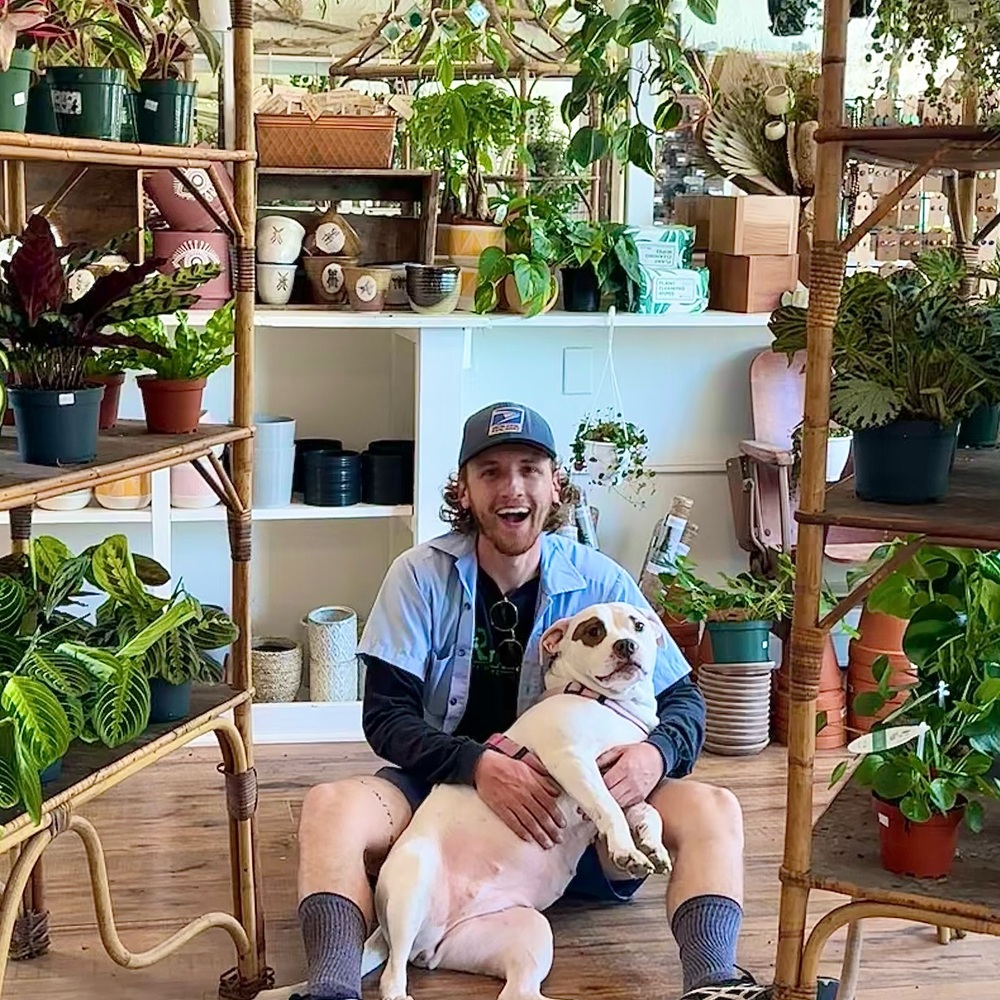 men with indoor plant and pet dog