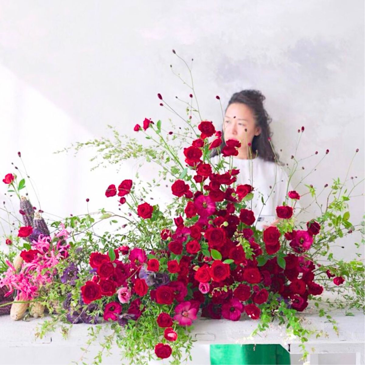 Jung standing behind a floral design of red roses