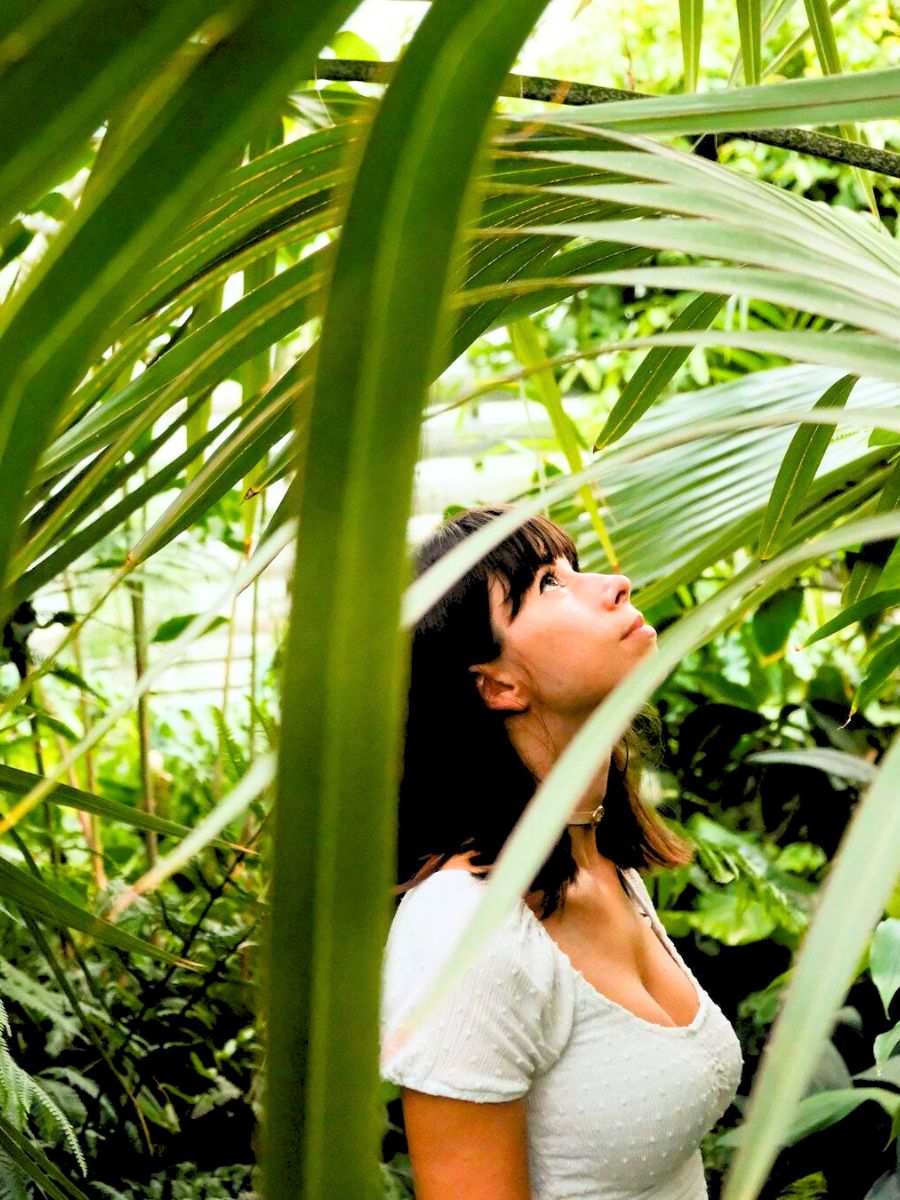 Girl admiring green plants in botanical garden