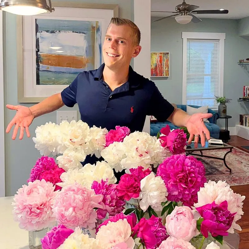 A man presenting beautiful peonies flowers arranged on vases