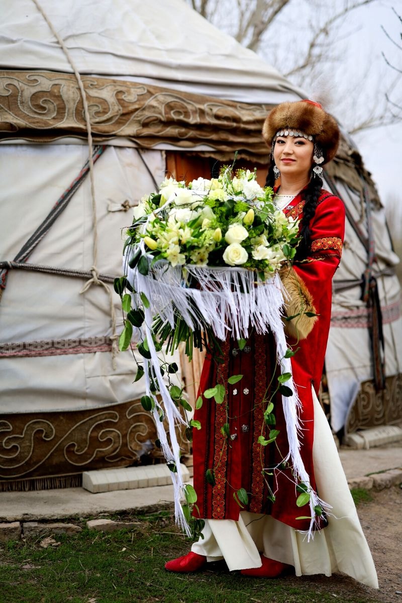 Krygyz woman holding a luxury bouquet featuring snow white tulips - design by Petr Anokhin