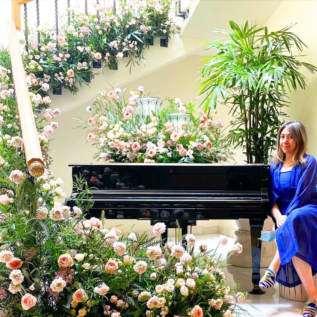 Bibi Hayat next to a piano decor full of flowers