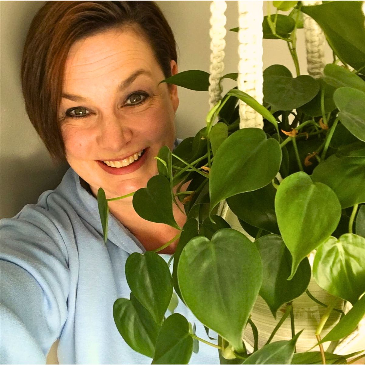 a woman posing with well-grown heart-leaf philodendron