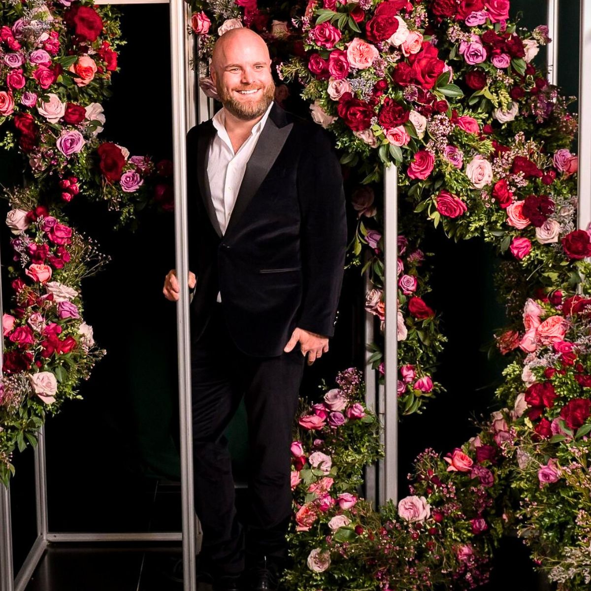 Larry Walshe surrounded by pink and red roses