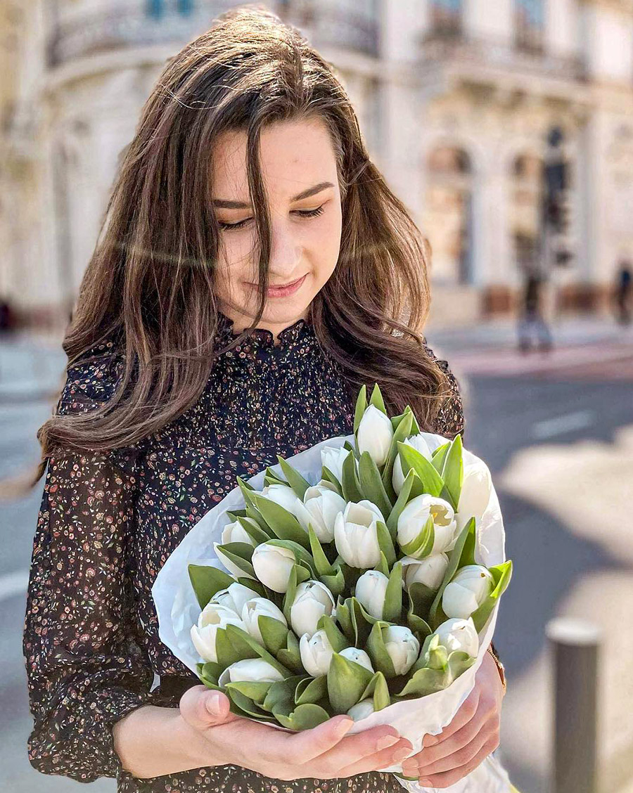 Model with pack of white tulips in the city