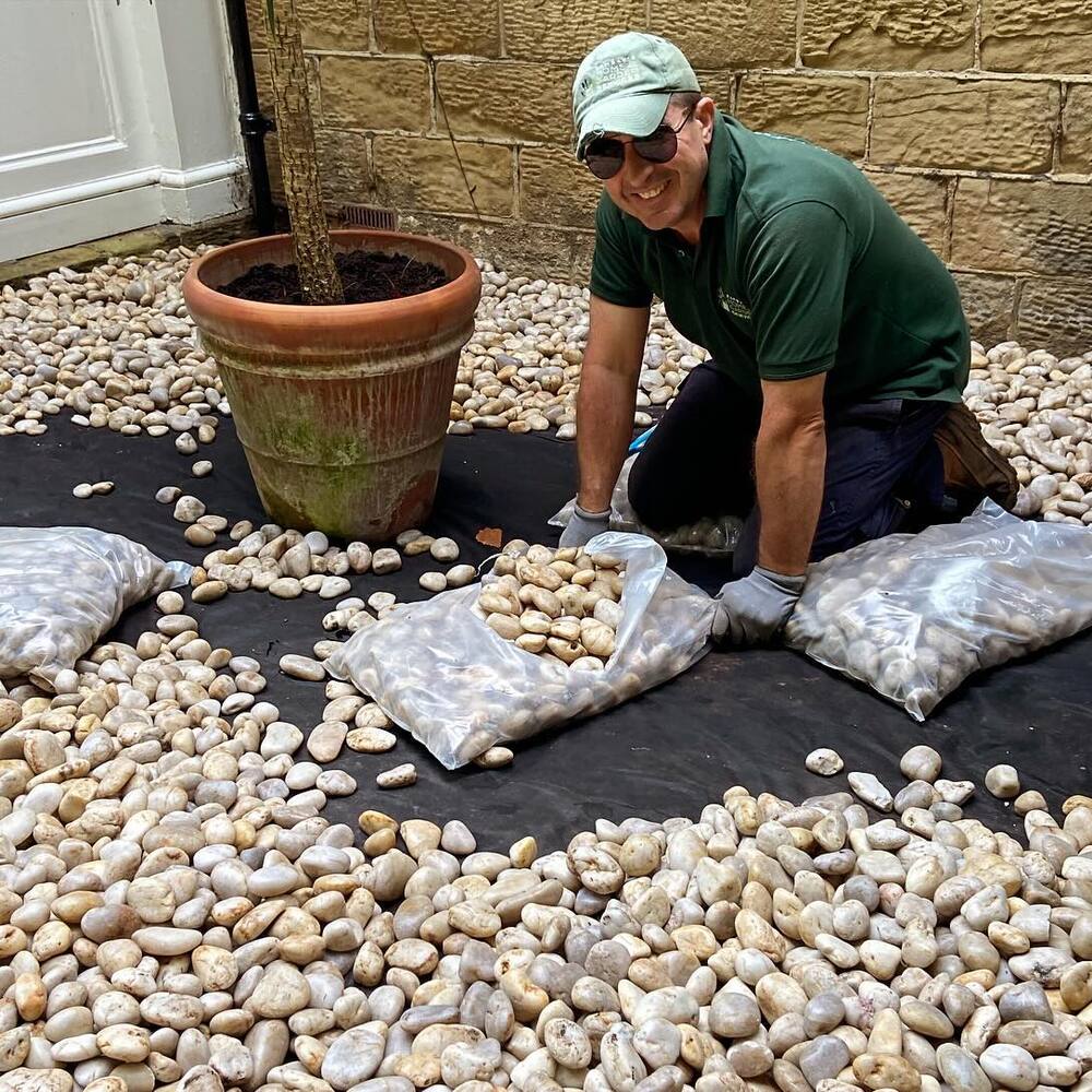 man arranging stones at garden area