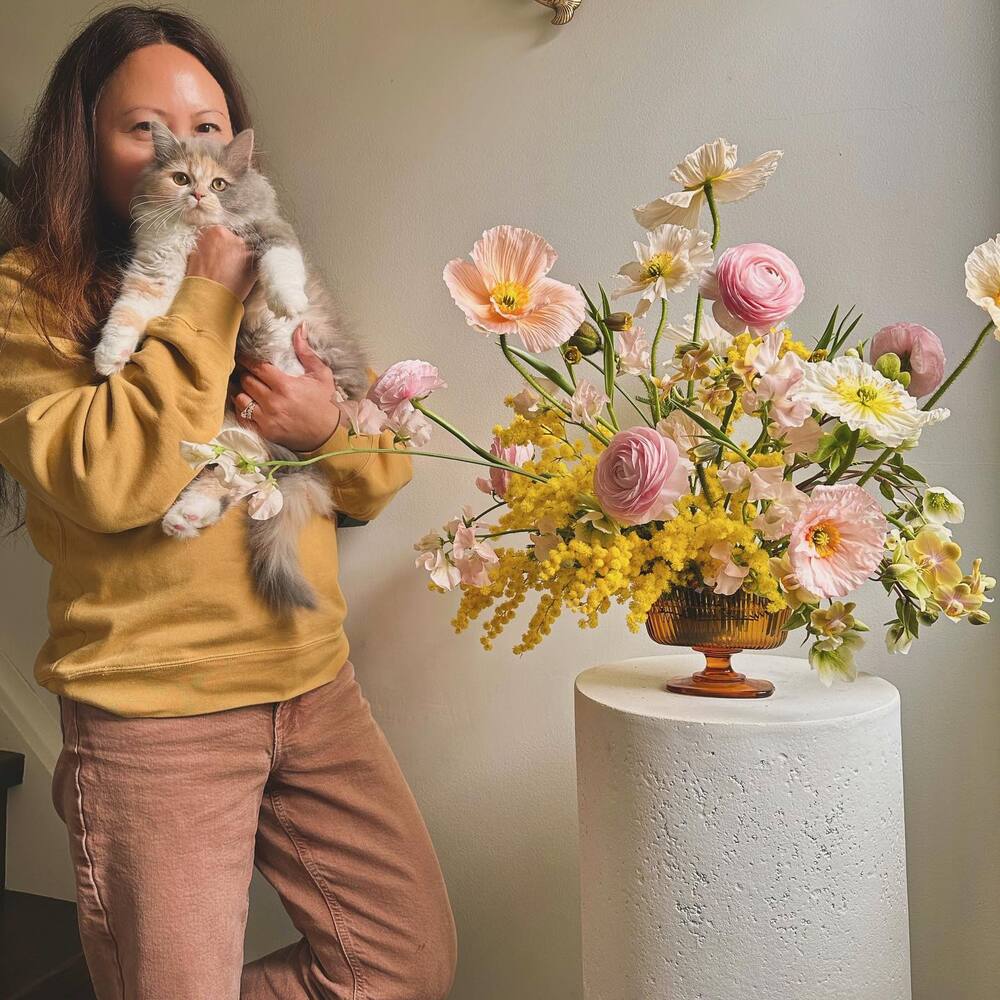 lady with cat near flower arrangement