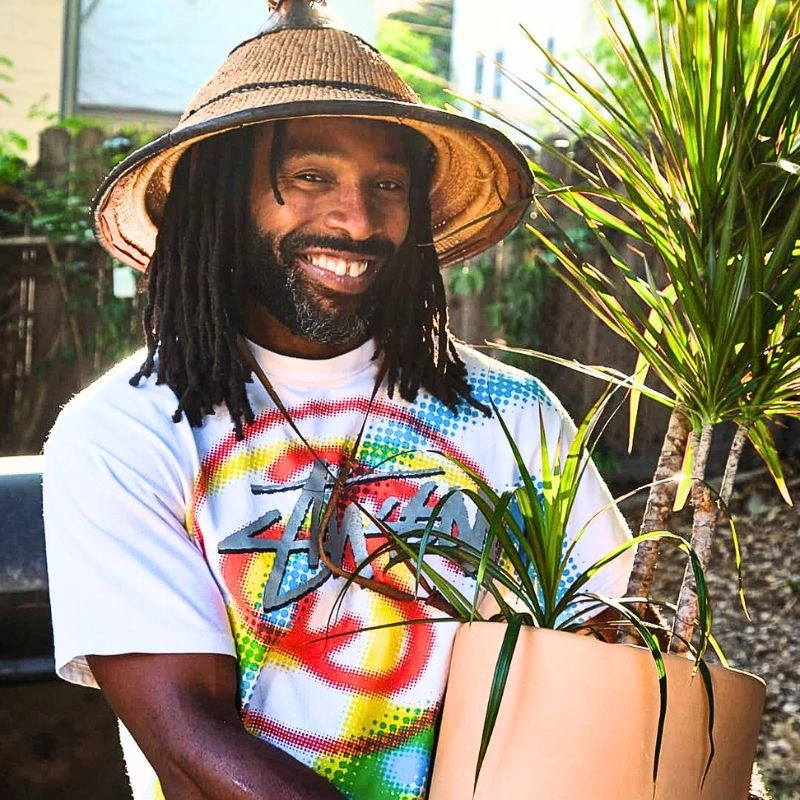 man smiling while holding his dracaena marginata plant