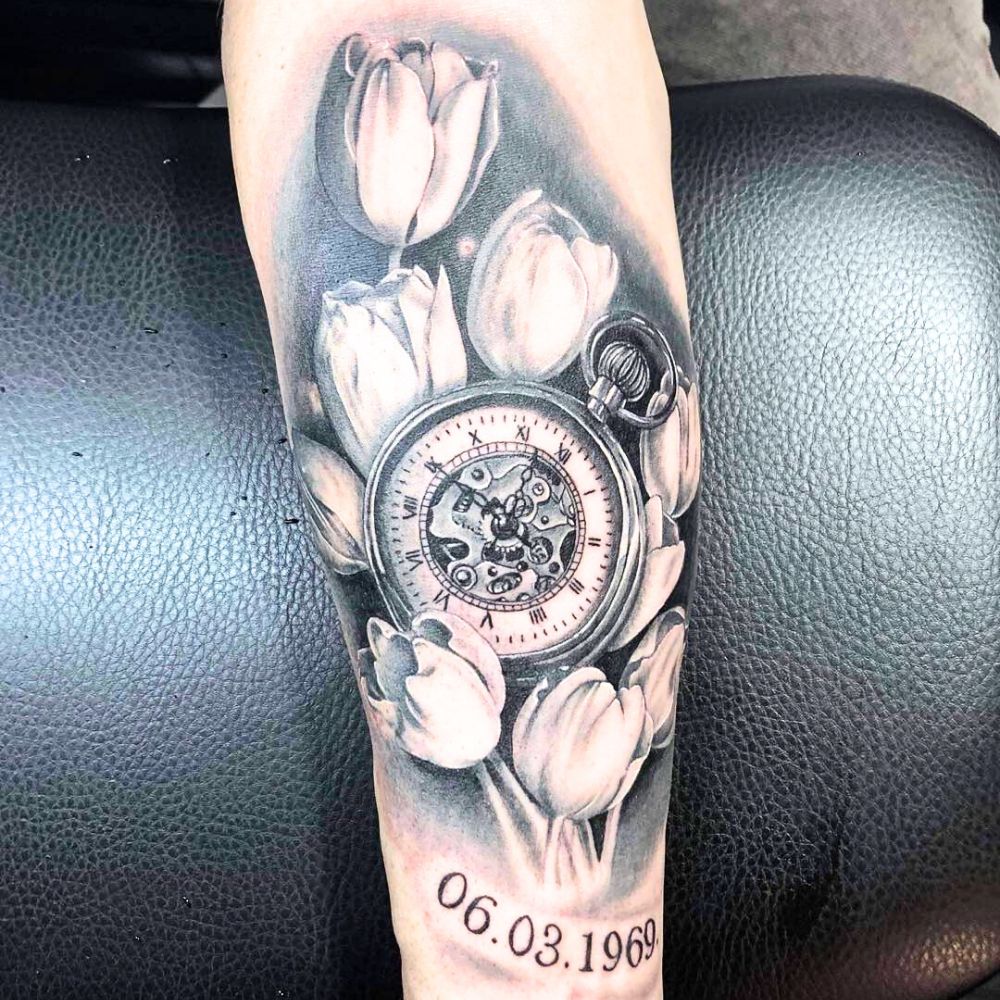 Tattoo of a pocket watch among white tulips.