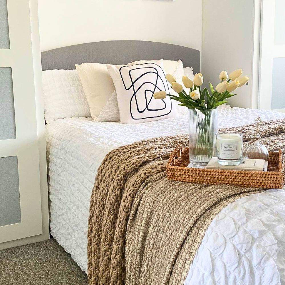 Cozy bedroom with white bedding and tulips.