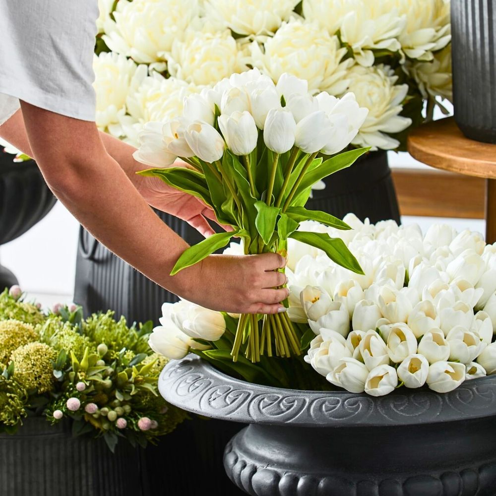 Arranging white tulips in a decorative vase.