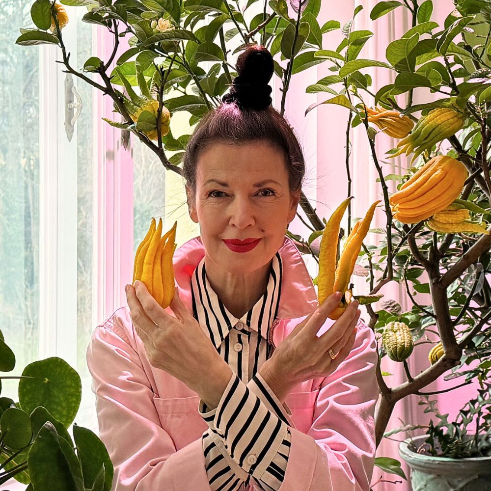 Woman holding Buddha's hand fruit by a tree.