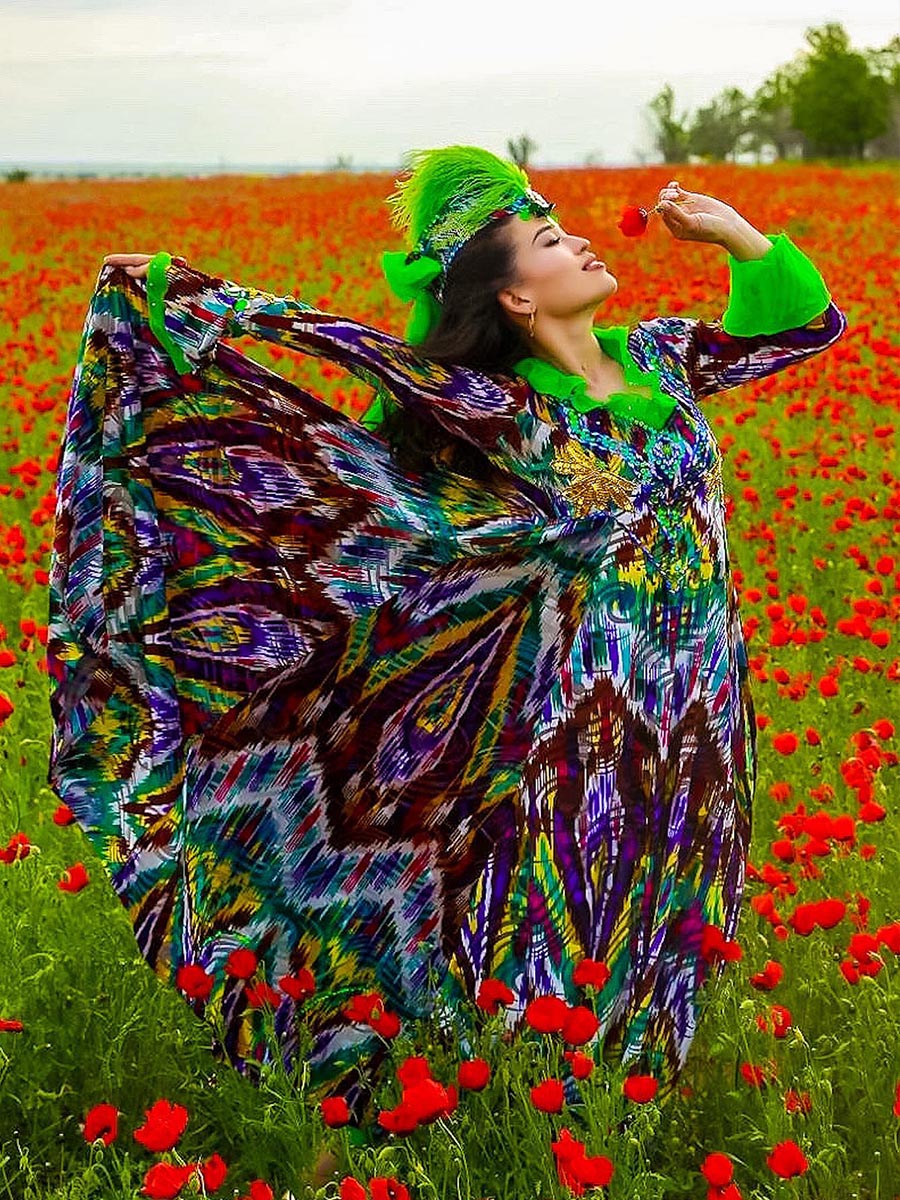 Kazakh woman in traditonal green dress in poppy field