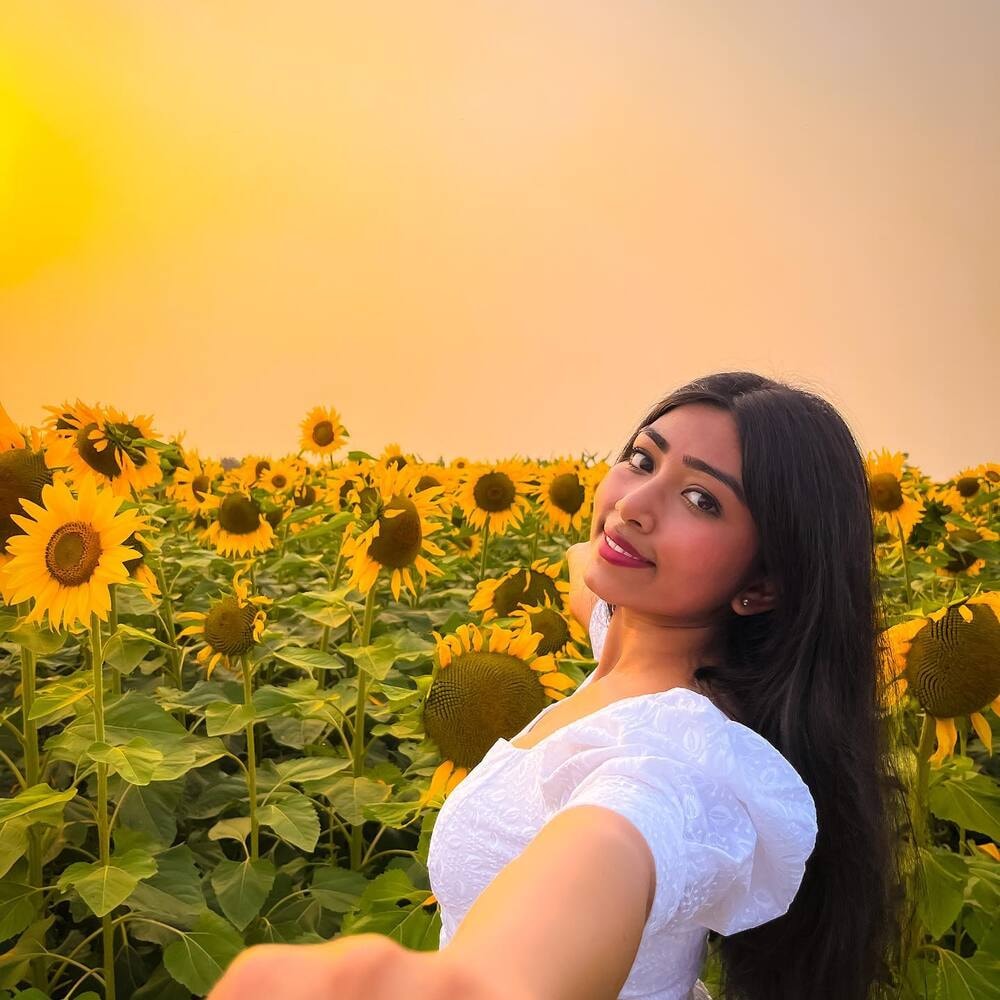 Smiling woman in a sunflower field at sunset