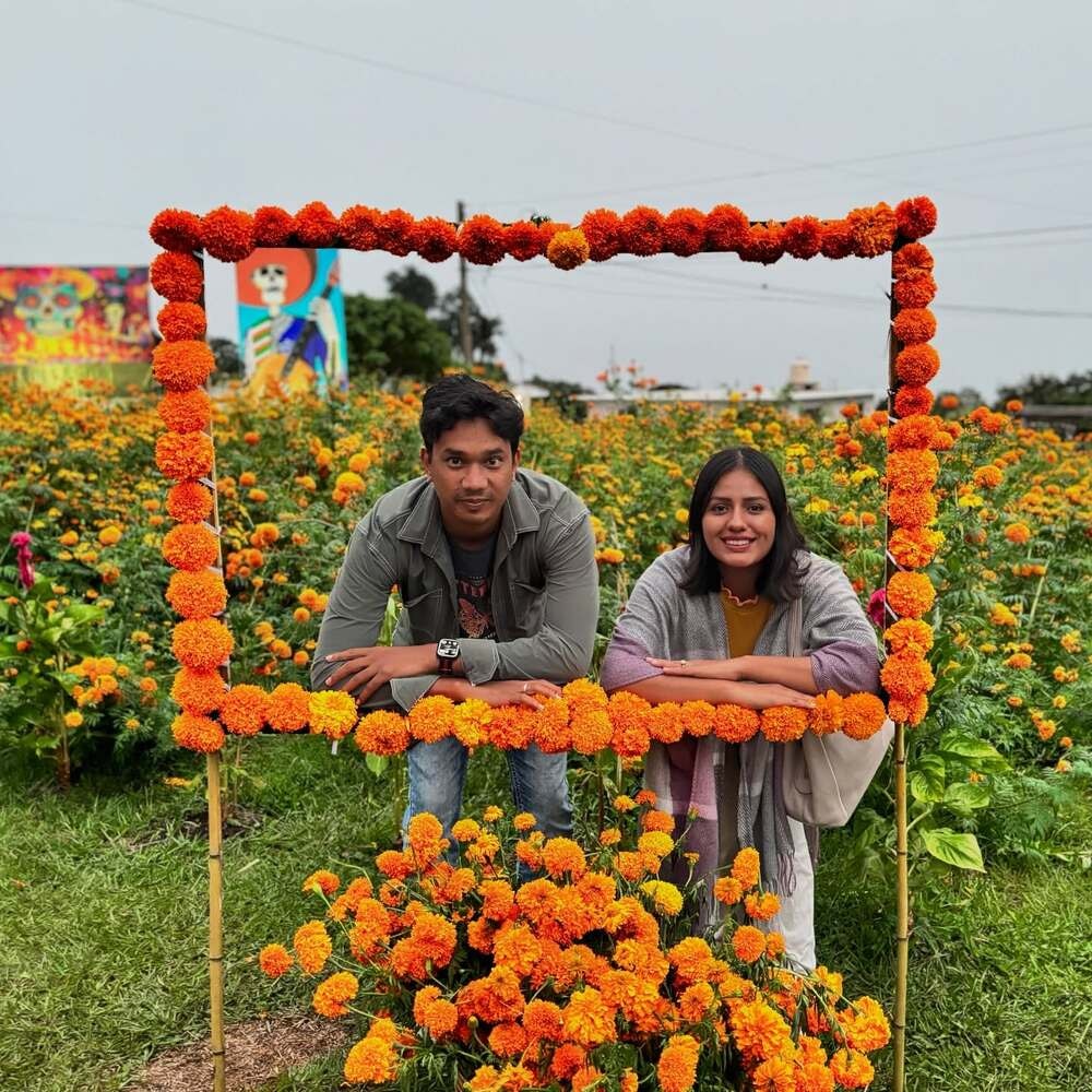 Two people framed by marigold flowers in a field 