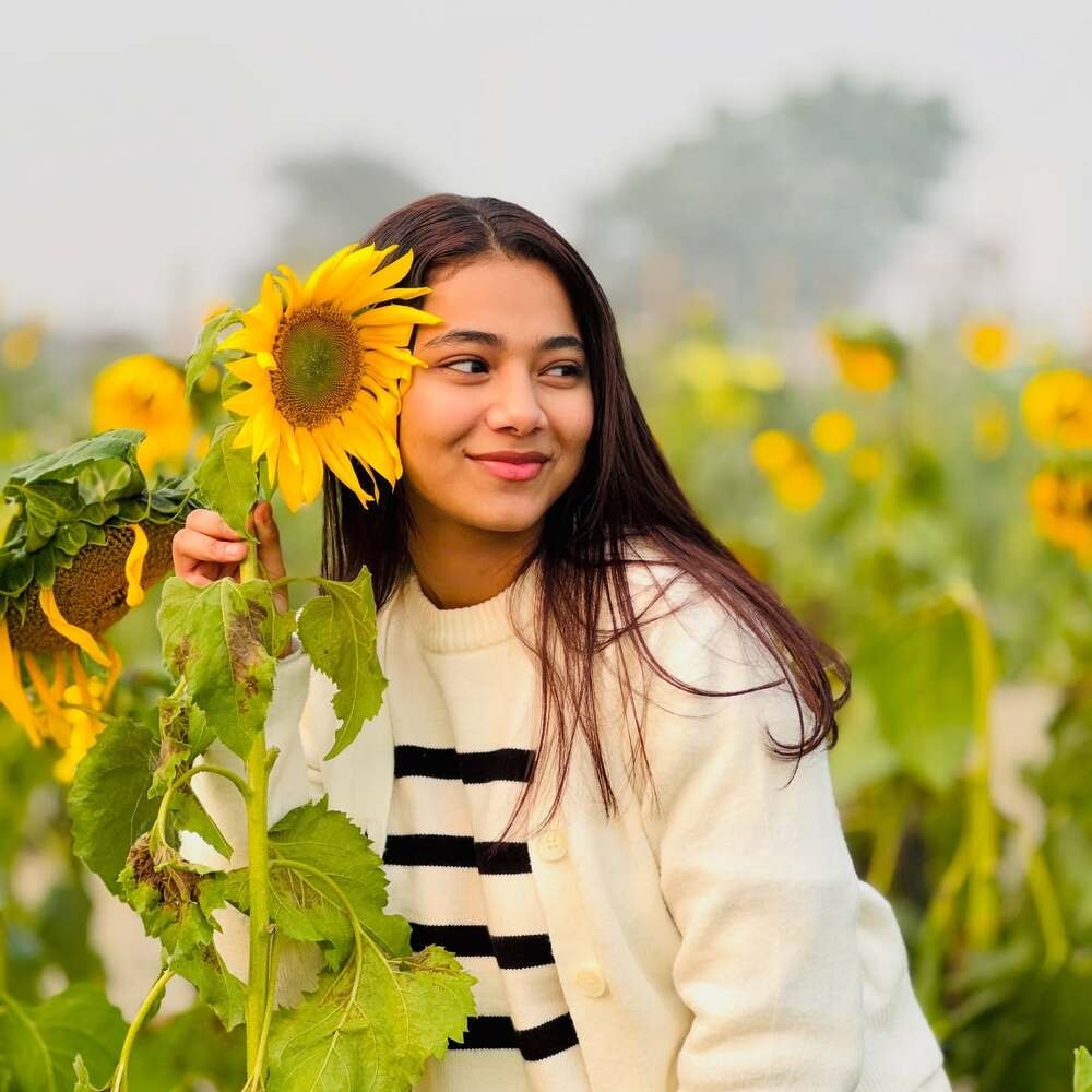 Woman poses with a sunflower in a field 