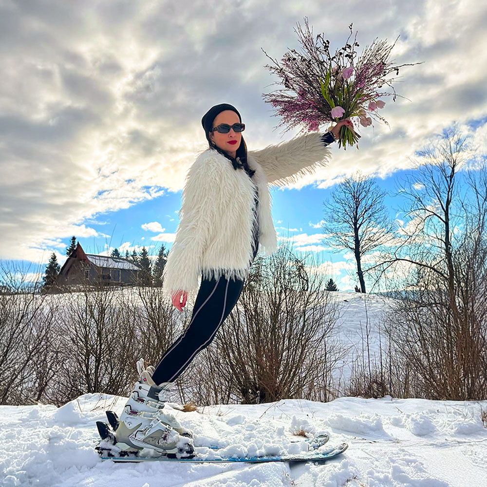 Olena Driuchan on skis with floral bouquet