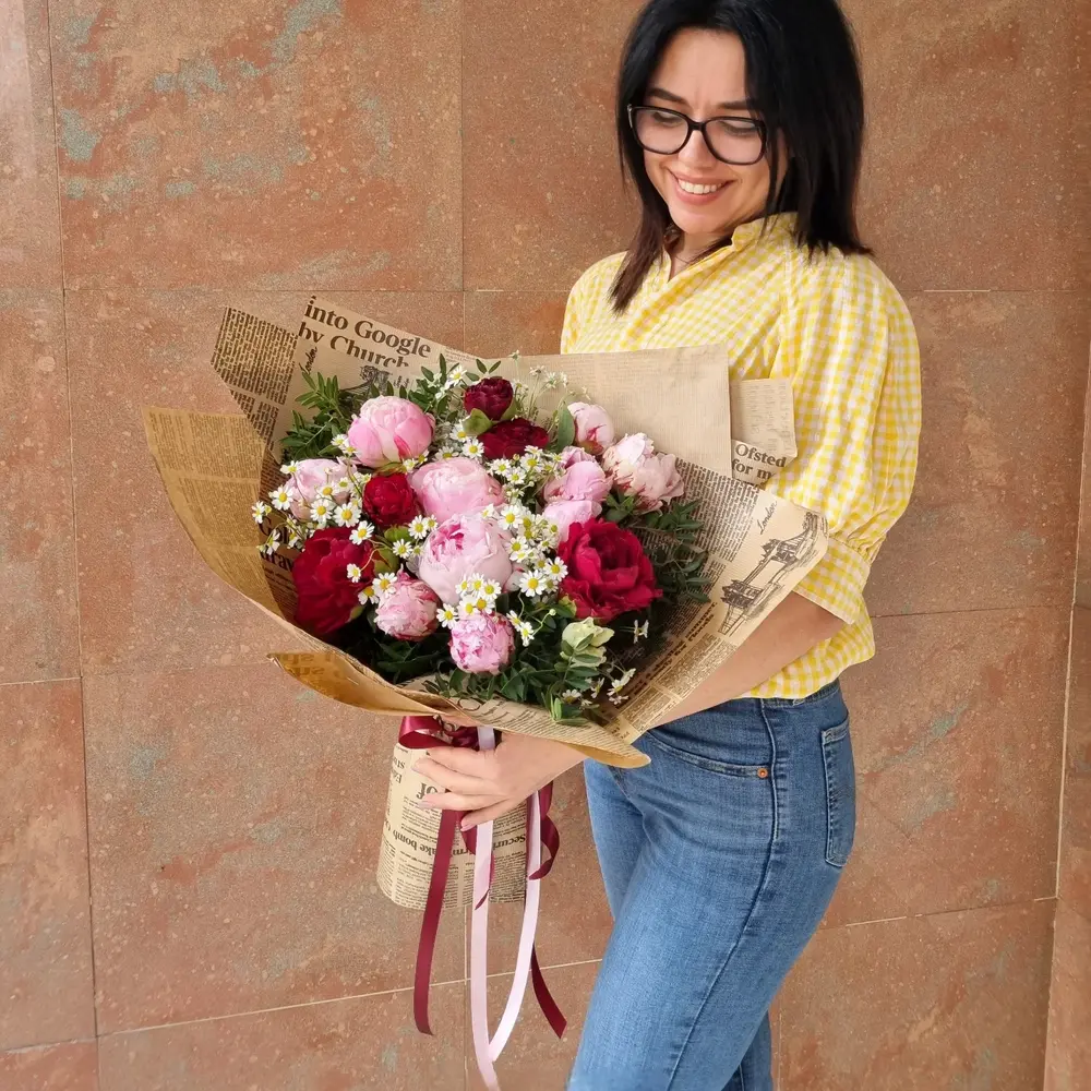 a florist posing with her bouquet wrapped with newspaper and ribbons a florist posing with her bouquet wrapped with newspaper and ribbons