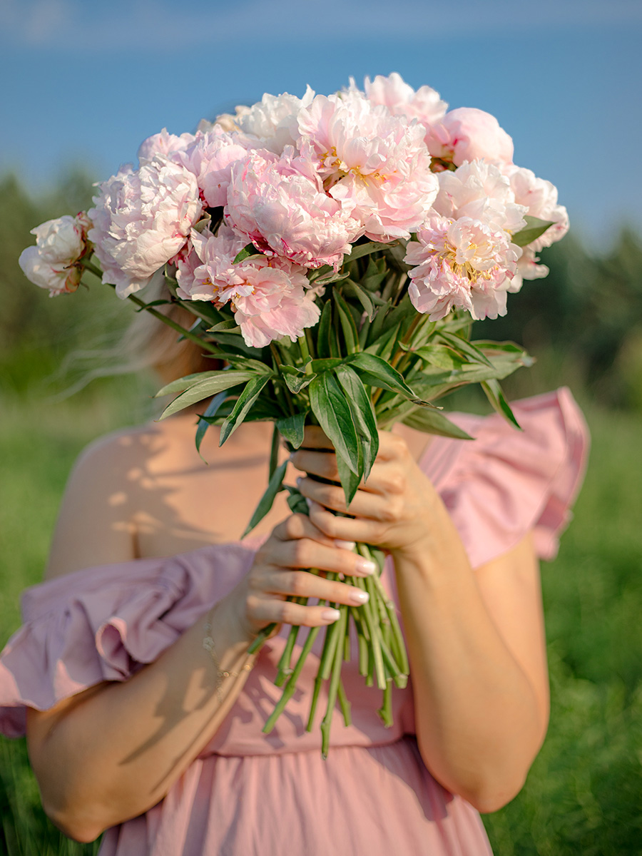 Model in light pink dress with light pink peonies